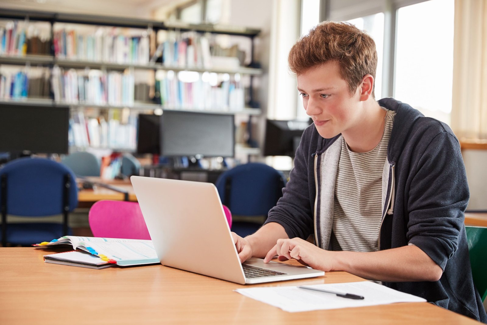 Mannelijke student werkt op laptop in universiteitsbibliotheek